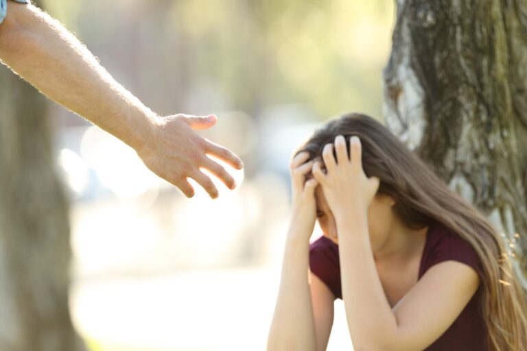 A distressed woman next to a tree.