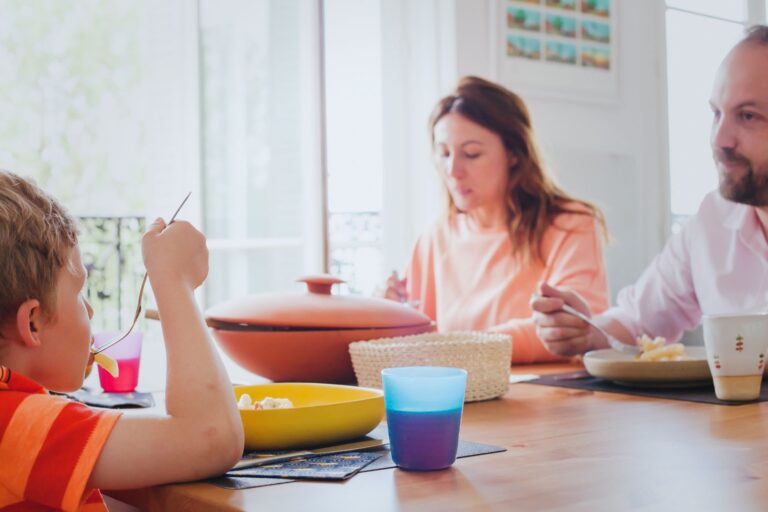 A man and a woman eating food with a young child.