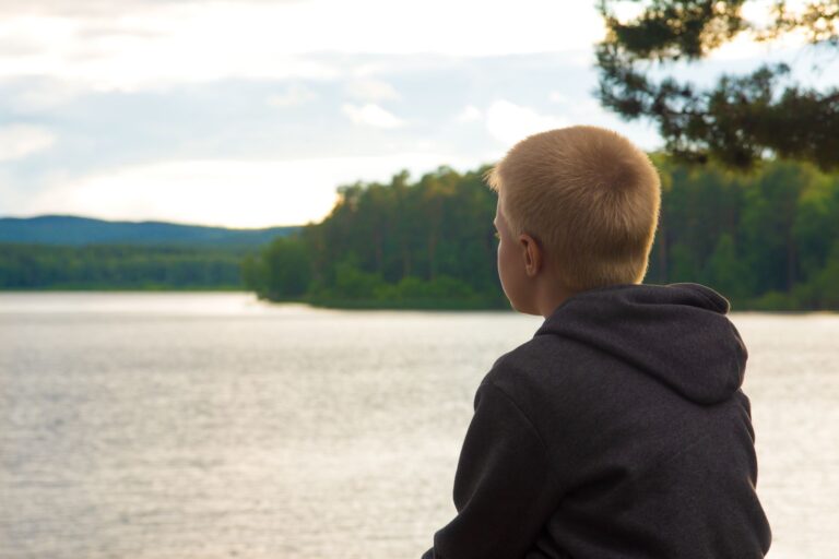 Boy looking out across a lake.