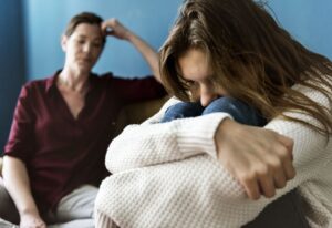 A woman clutching her knees while talking to a therapist.