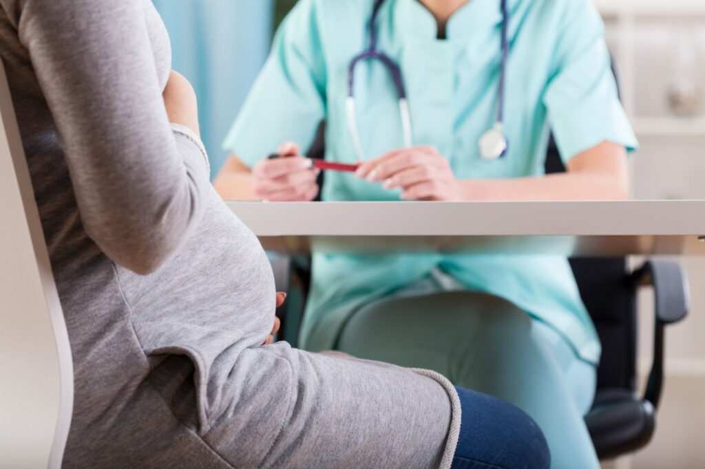 A pregnant woman talking to a doctor.