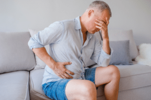 Man dealing with opioid induced constipation, sitting on a toilet.